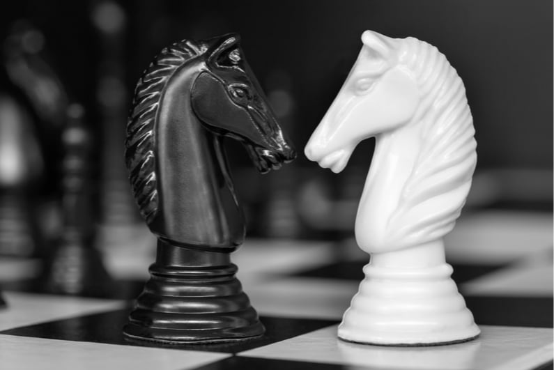 Black and white chess knights facing each other