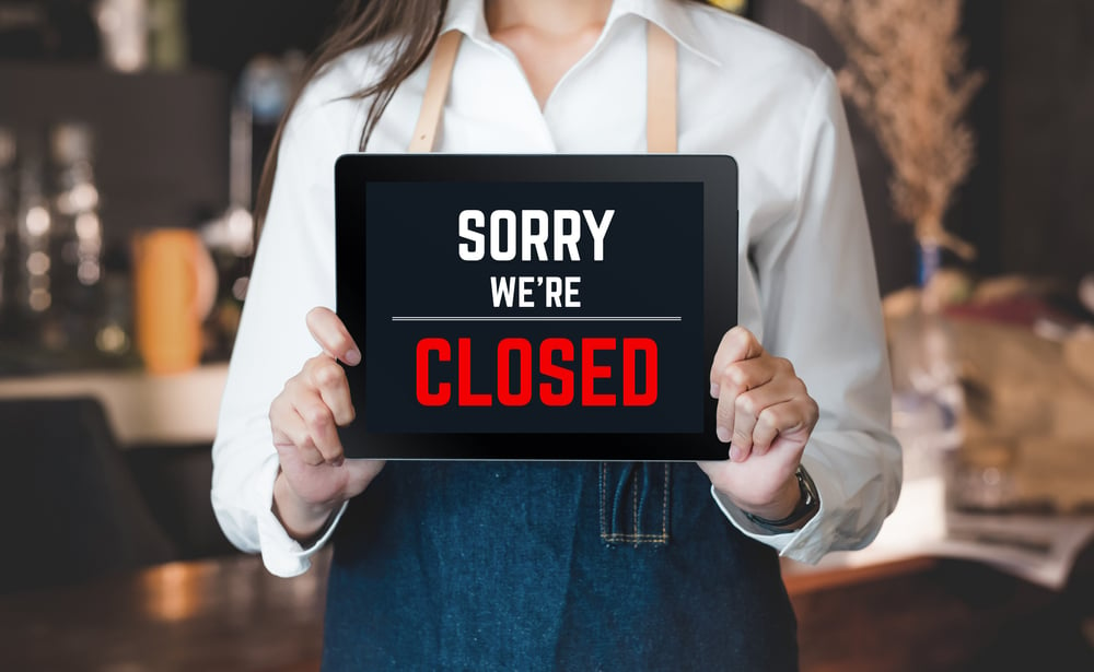 Bar worker holds sorry we're closed sign