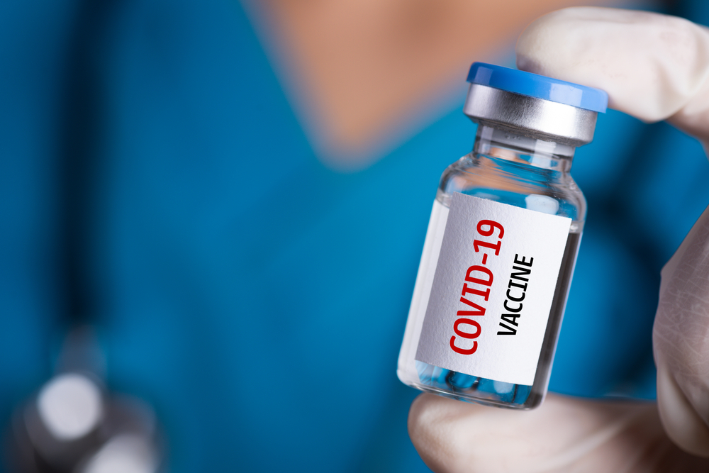 gloved doctor's hand holding Covid-19 vaccine vial