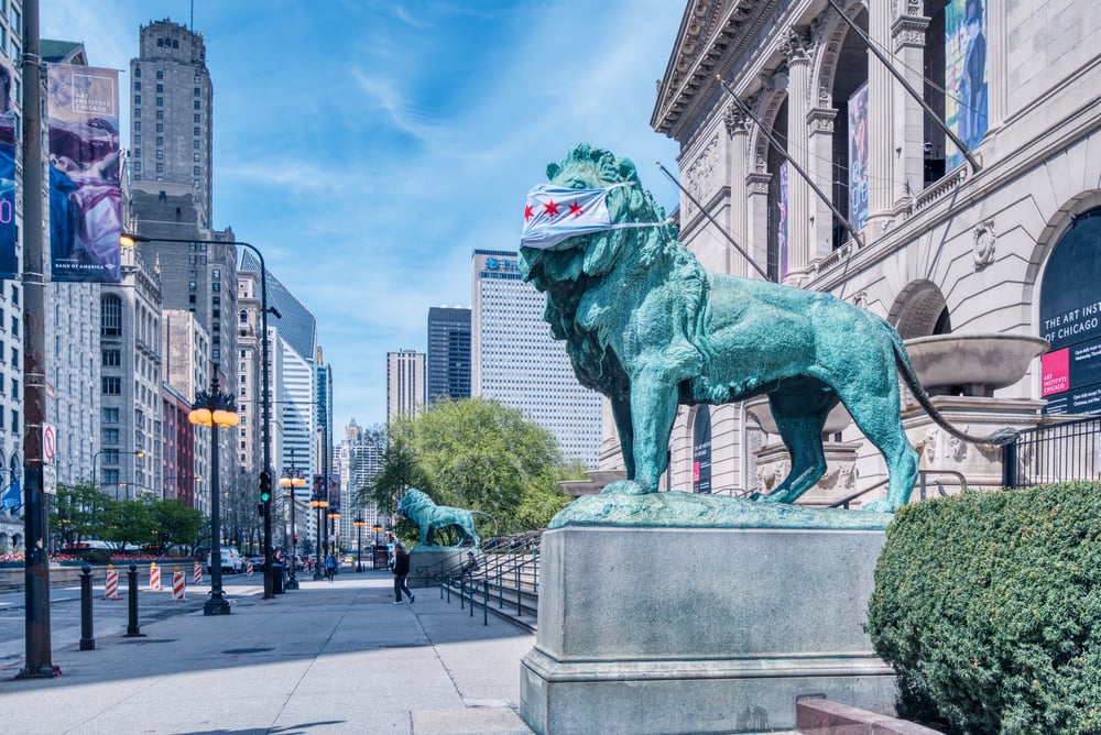lion statue in Chicago wearing face mask with Chicago flag