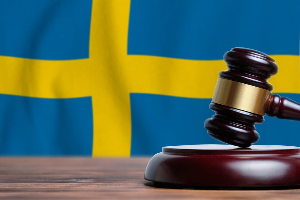 judge's gavel with flag of Sweden in the background