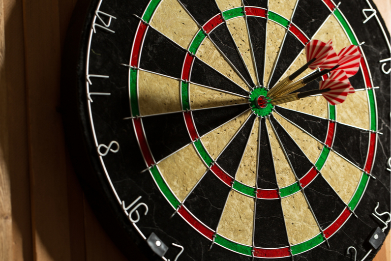 Three darts hitting the bullseye of a dartboard