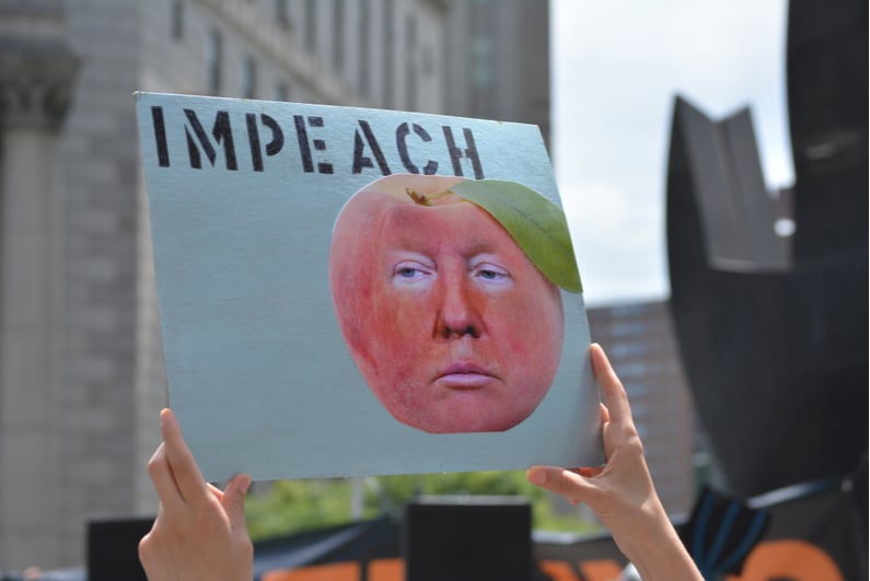 Protest sign reading "IMPEACH" with a picture of Donald Trump's face as a peach