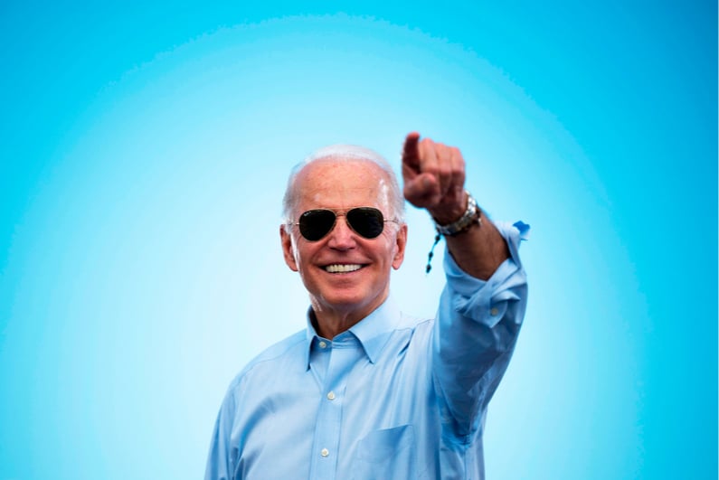 Joe Biden smiling against a sky blue background