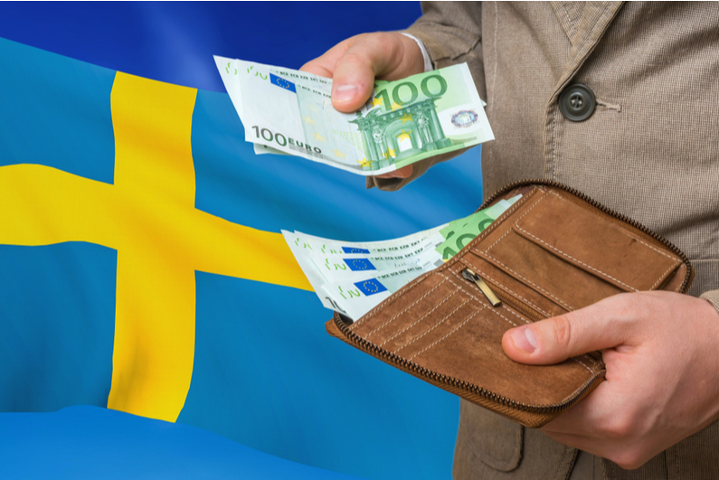 Man taking money out of his wallet in front of the Swedish flag