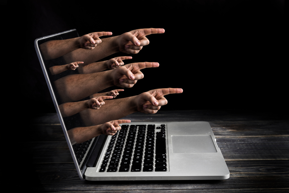 Various hands pointing out of a laptop screen