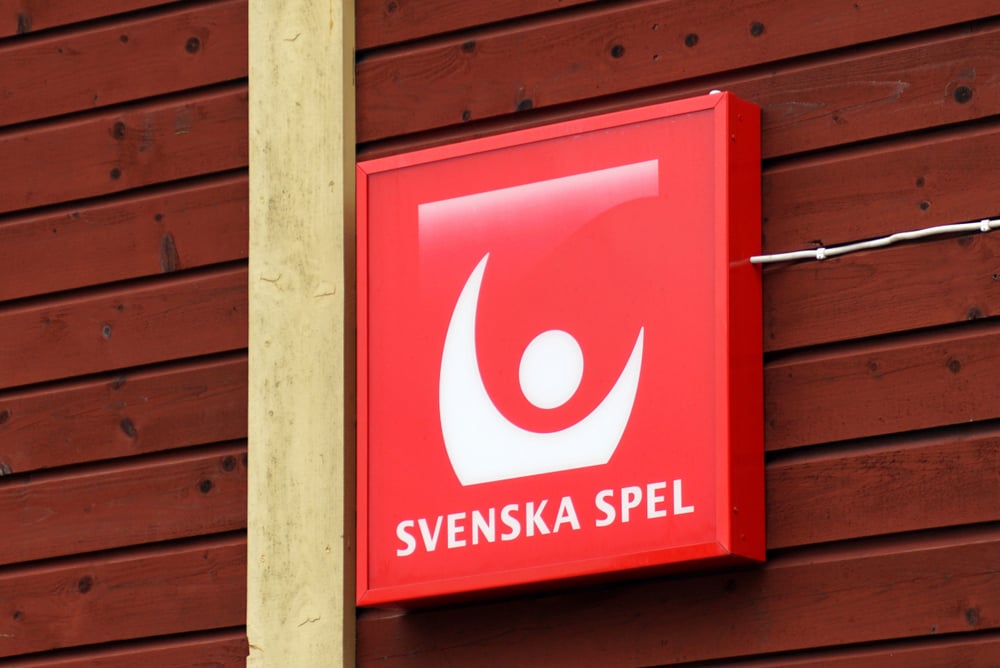 Red and white Svenska Spel logo on wooden wall