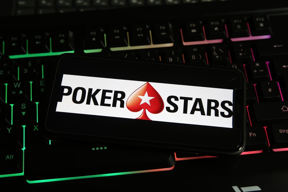 PokerStars logo on smartphone lying on gaming laptop keyboard