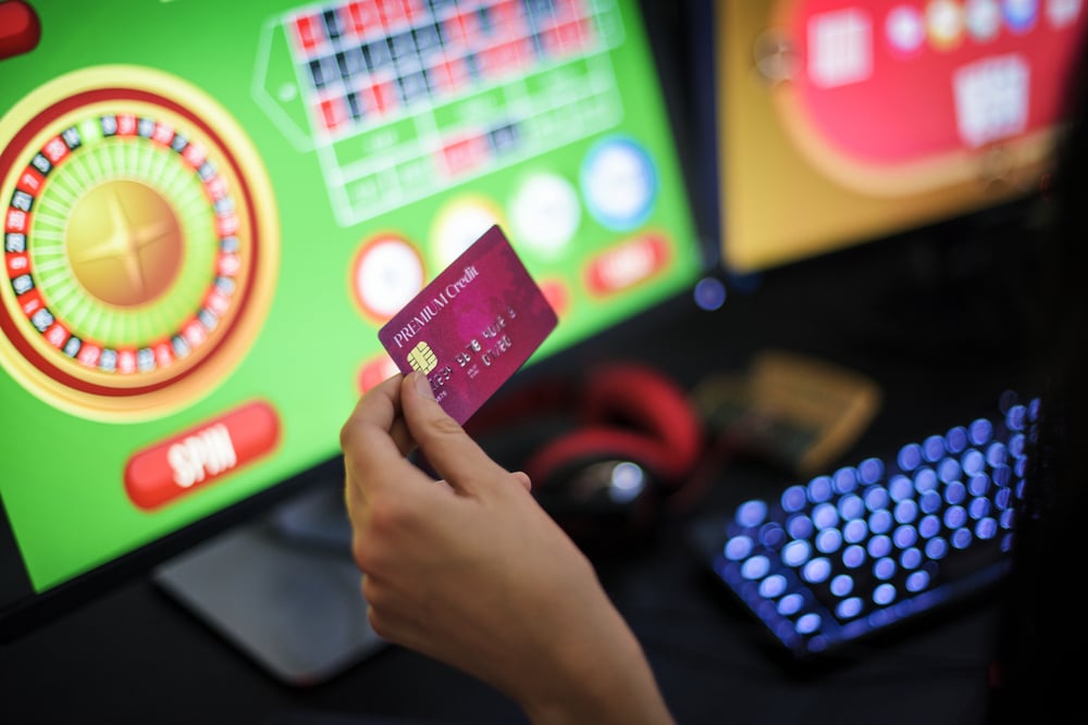 Person holding debit card while playing online casino