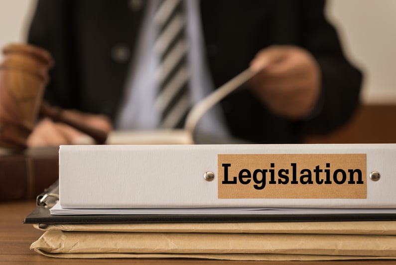 Man looking over documents with binder labeled "Legislation" on the desk