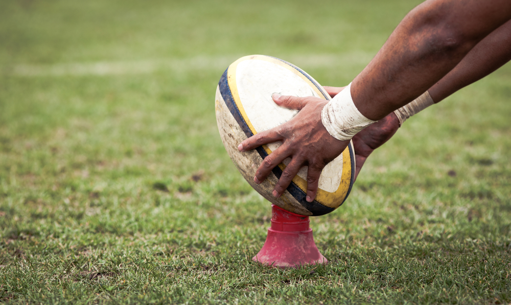 rugby player prepares to kick oval ball