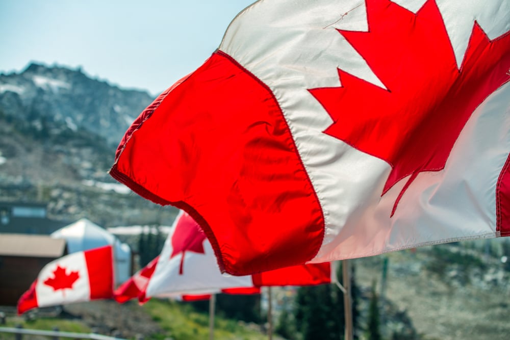flags of Canada against a mountain backdrop