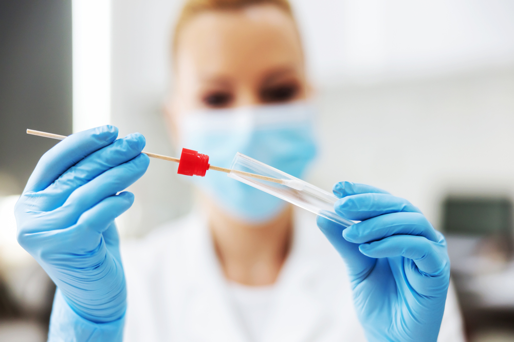 medical professional wears mask while handling a COVID-19 swab test