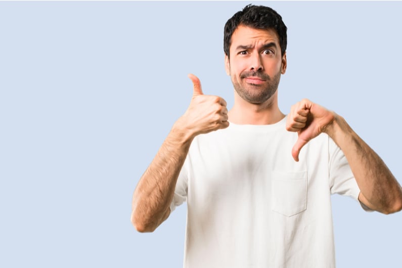 Man with a goofy, quizzical look on his face giving thumbs up and thumbs down