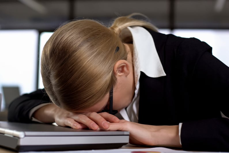 Dejected woman with her head on a closed laptop