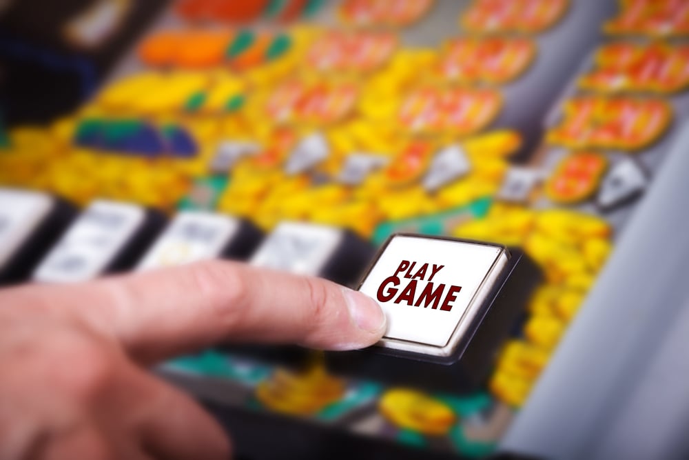 index finger presses Play Game button on gambling machine