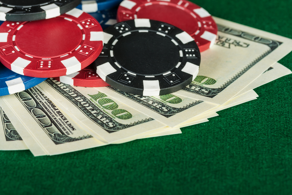 poker chips and hundred-dollar bills on green poker table