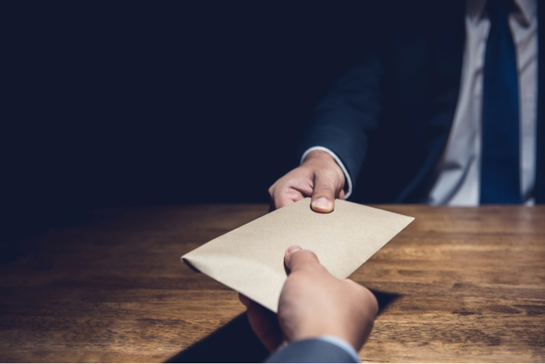 Businessman handing envelope to across a table