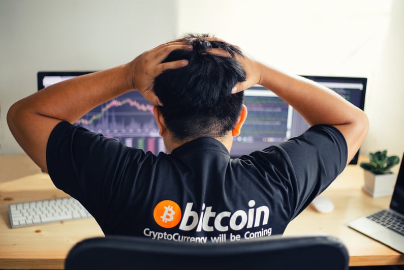 Man in Bitcoin shirt upset at charts on computer