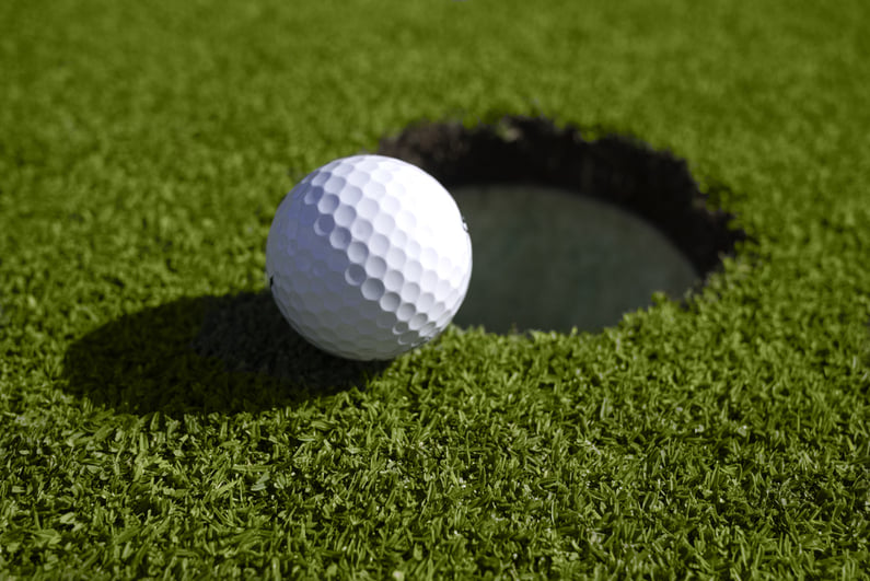 Golf ball sitting on edge of hole