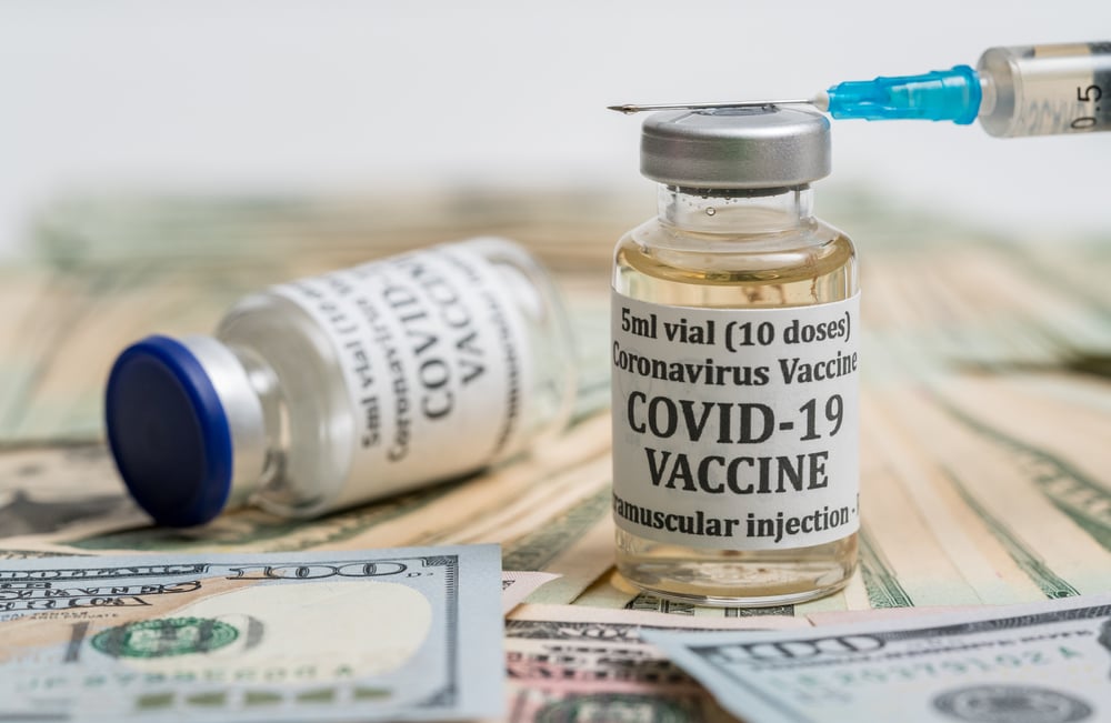 COVID-19 vaccine phial and syringe with dollar bills below