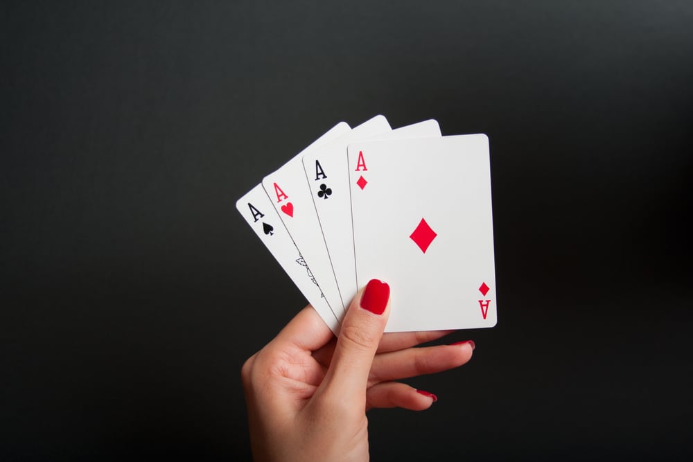 woman's hands hold four of a kind poker cards