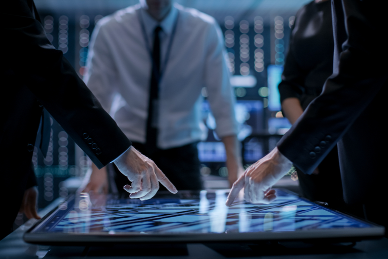 Business people standing around large tablet screen table