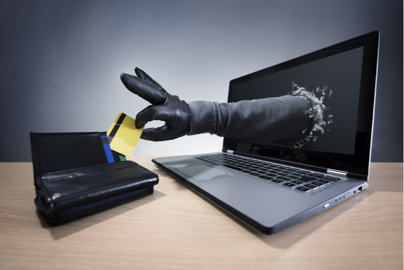 Gloved hand coming out of a laptop monitor and stealing a credit card from a purse