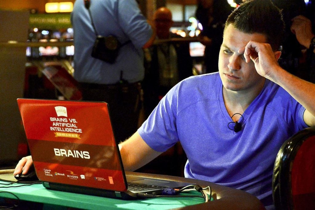 Doug Polk at his laptop on a poker table