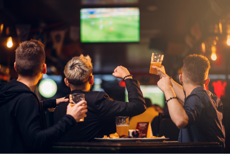 Three men cheering at a sports bar