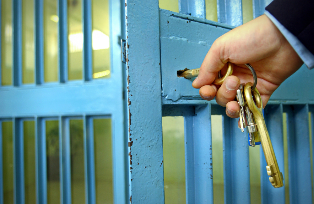 prison guard's hand locks prison cell door