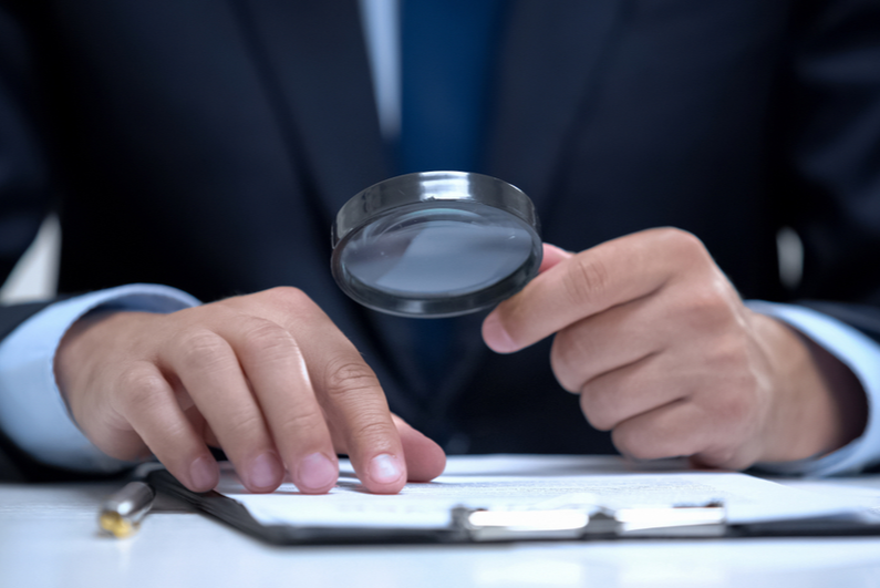 Businessman reading document through magnifying glass