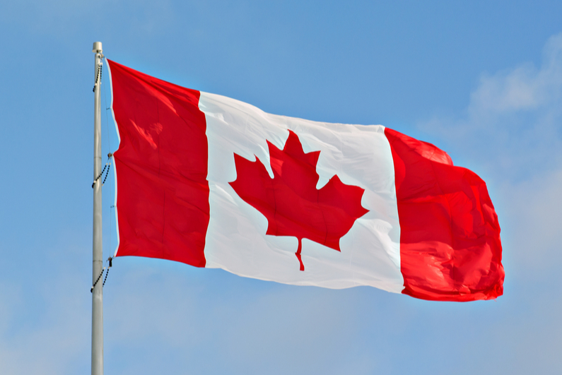 Canadian flag flying against a blue sky backdrop