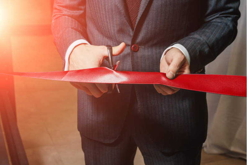 Man cutting red ribbon