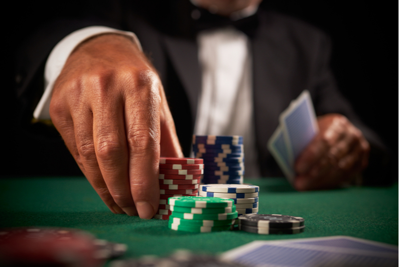 male hand moving casino chips on a poker table