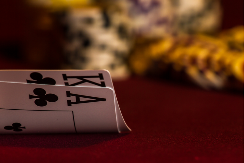 Ace-King of clubs with chips blurred in the background