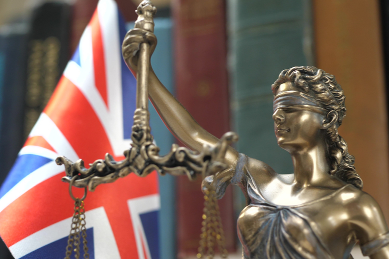 Statue of Lady Justice with UK flag background