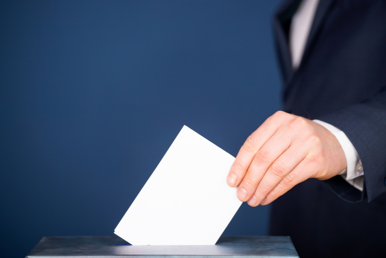 Person putting a vote into a ballot box