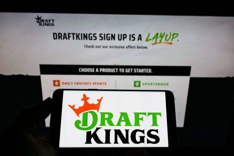 Smartphone with logo of DraftKings on screen in front of website