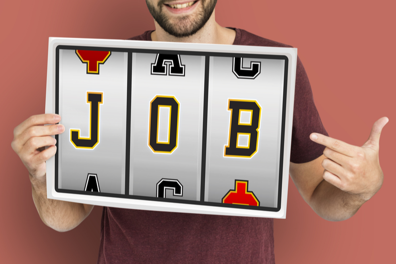 Man holding board with "JOB" spelled out in the form of slot reels