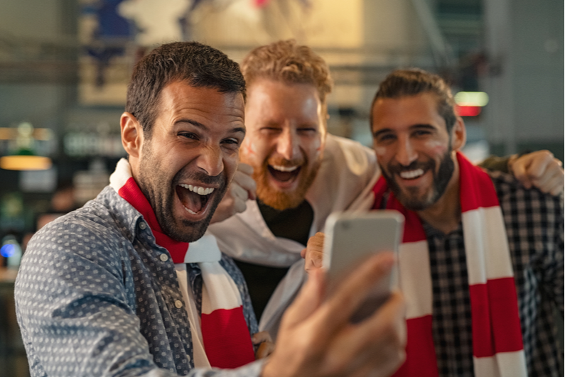Men cheering at smartphone