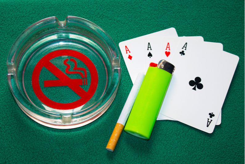 ashtray, cigarette, and lighter on felt with cards