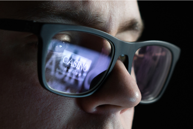 Close-up of man's face with "casino" reflected in his glasses