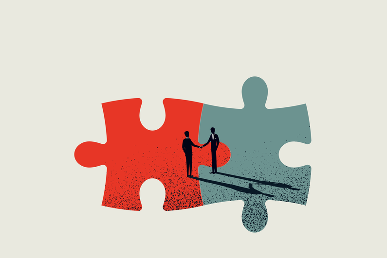 Silhouettes of two businessmen shaking hands over joined puzzle pieces