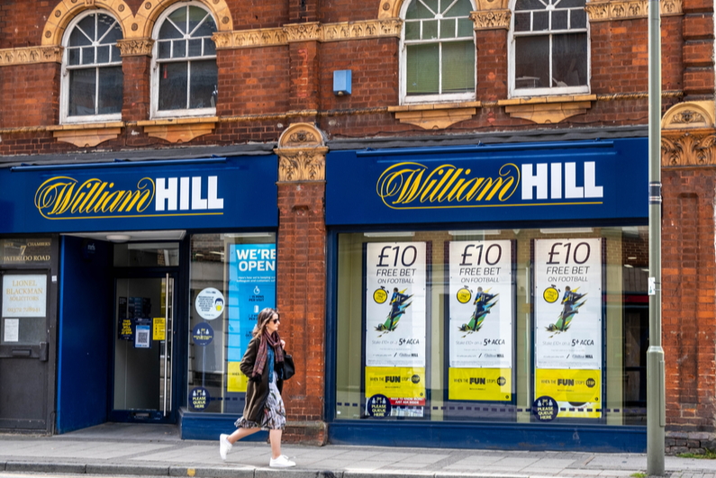 Woman walking past William Hill betting shops on UK high street