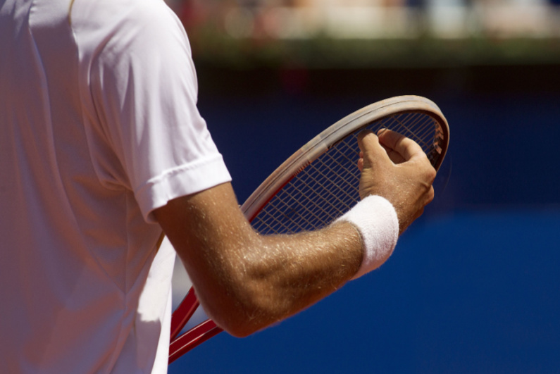 Closeup of tennis player checking strings on his racquet