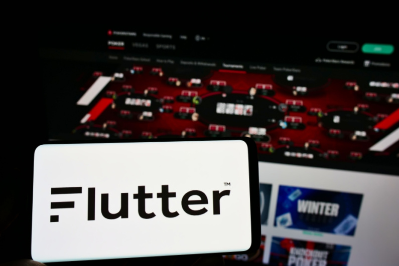 Flutter logo on a smartphone in front of online poker tables