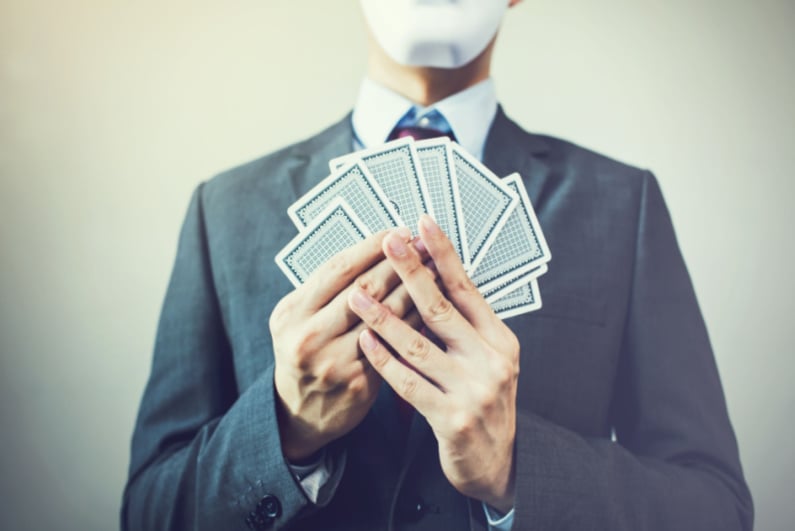 Masked man holding playing cards