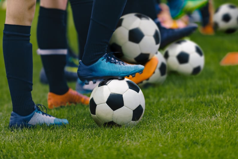 Closeup of soccer balls at players' feet