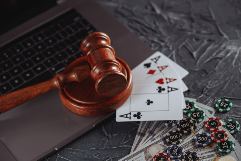 Judge's gavel on a laptop with playing cards, money, and poker chips